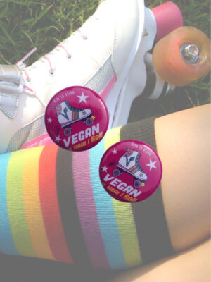 A picture of a pair of vinatge roller skates with an overlay of the product being sold which is a small (25mm) sized badge with a rooler skate and the words "Vegan Skater - Thats how I roll" on it. Designed by Viva La Vegan.