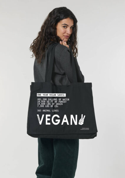 1 year vegan canvas shopper being worn. Black with white print by Eco ethical brand Viva La Vegan.