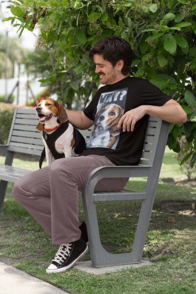 Man sat on a park bench stroking a beagle .wearing brown trousers and a black shirt with a large painted beagle design with the word WHY. By Viva La Vegan