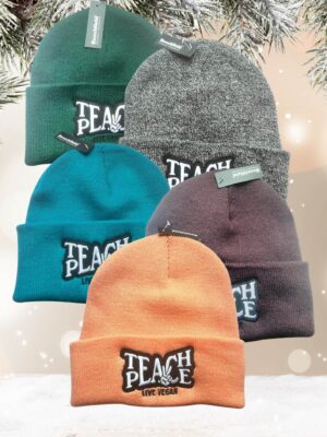 Flatlay photo of 5 cuffed beanies with a black and white embroidery 'Teach Peace - Live Vegan.