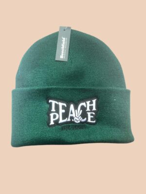 Flatlay photo of a cuffed beanie in Bottle green colour with a black and white embroidery 'Teach Peace - Live Vegan.