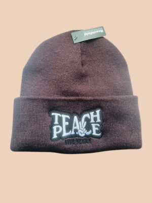 Flatlay photo of a cuffed beanie in plum colour with a black and white embroidery 'Teach Peace - Live Vegan.